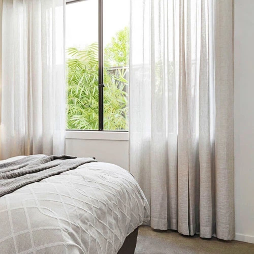 Linen sheer curtains hanging over a window in a bedroom