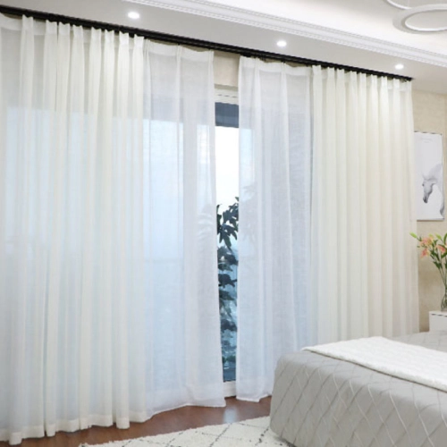 Voile sheer curtains hanging over a large window in a bedroom