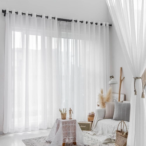 A bright white sheer curtain is tied back to the side, revealing white horizontal blinds behind it.