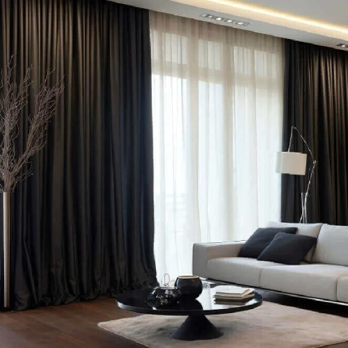 Luxury living room with white sofa and dramatic layered blackout curtains over bright sheer drapes