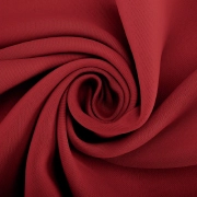 Maroon blackout curtain fabric tightly swirled to show its texture and deep, rich color.