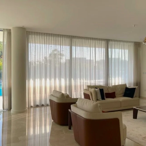 Modern living room with floor-to-ceiling sheer ripple fold curtains and polished marble floors