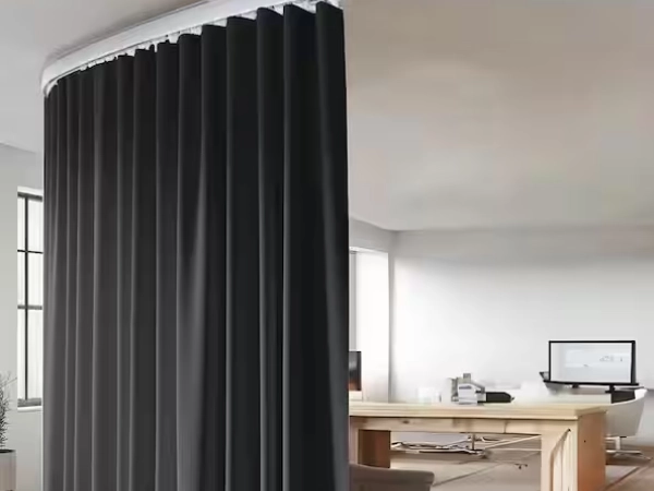 Modern office uses curved single track Blackout curtains Dubai to divide space near a large wooden desk.