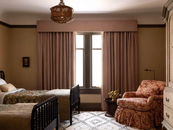 Pelmet blackout curtains Dubai in soft pink and taupe cover a central window in a cozy twin bedroom.