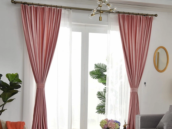 Stylish living room window featuring sheer curtains layered behind pink velvet Fleece-Backed Blackout curtains Dubai with tie-backs.