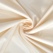 Swirls of lustrous Ivory blackout fabric draped and folded, showing its smooth texture and subtle sheen.