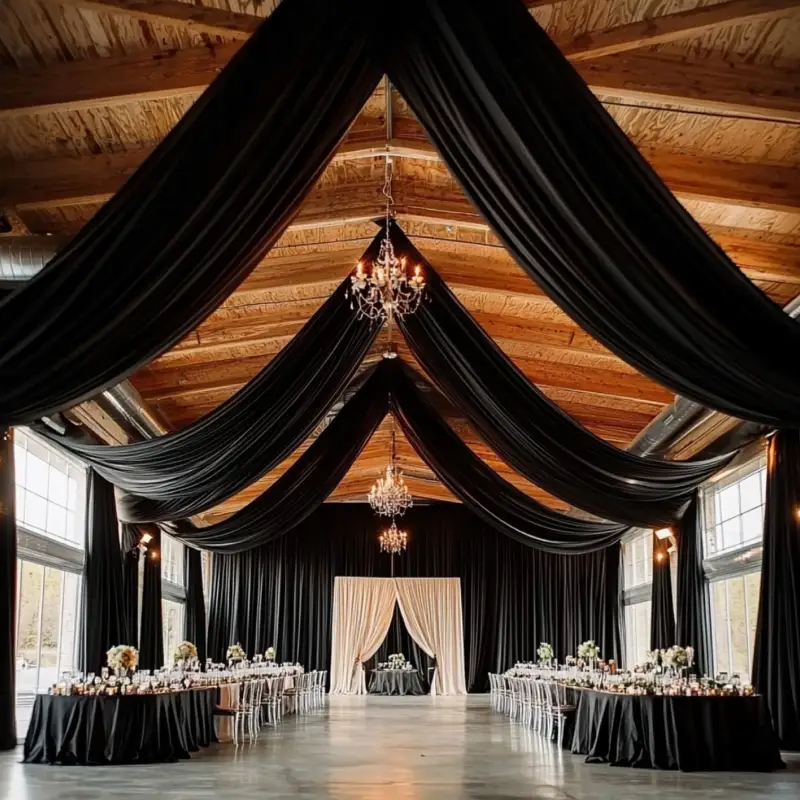 Chic industrial ballroom featuring dramatic black ceiling drapes and elegant window curtains.