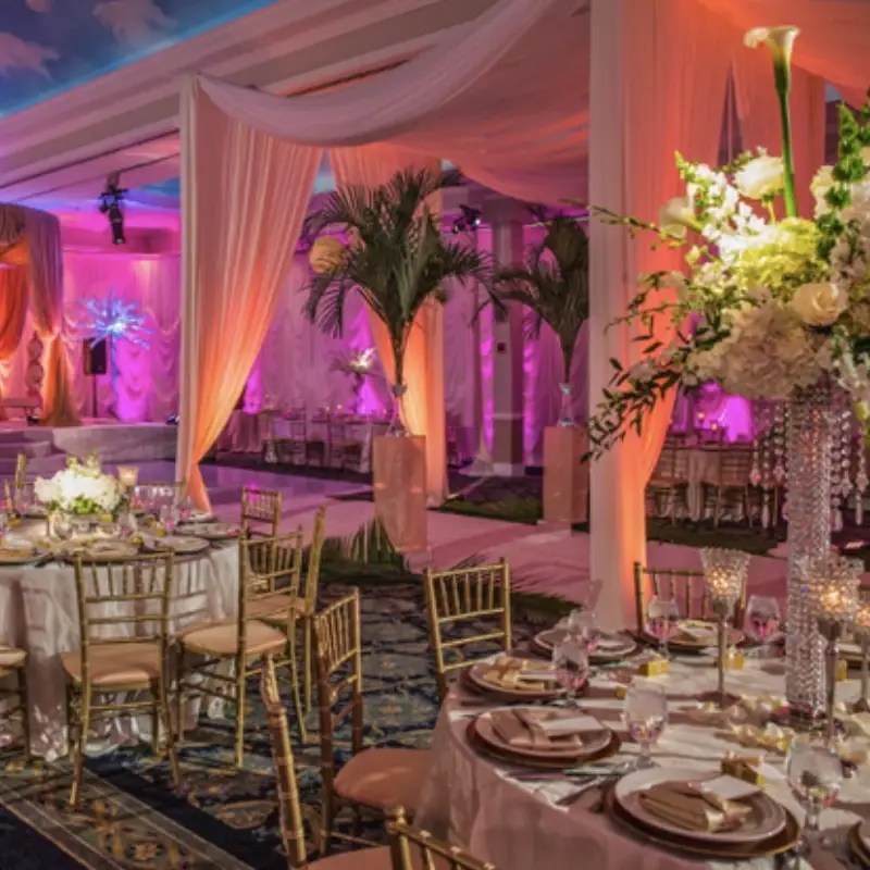 Luxurious ballroom curtains in soft peach and white, framing a gala with vibrant magenta lighting.