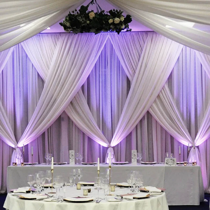 Modern reception hall curtains with white crisscross drapes and soft purple uplighting accents.