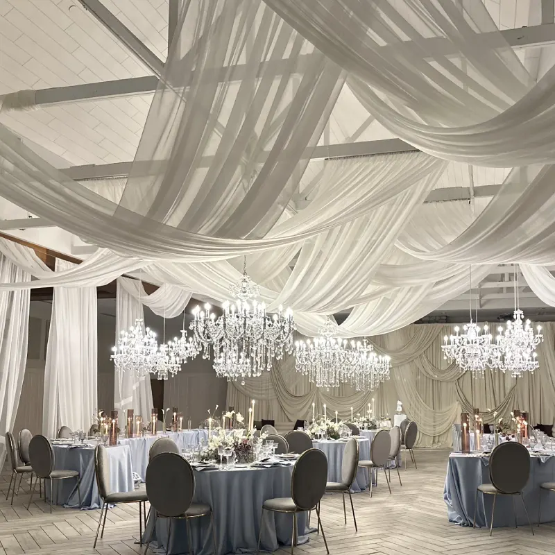Modern white ballroom covering and draping with crystal chandeliers for a luxury wedding reception.