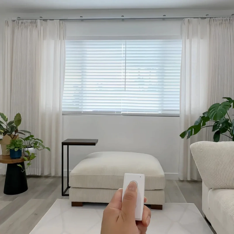 Modern white motorized curtains controlled by a remote in a minimalist living room.