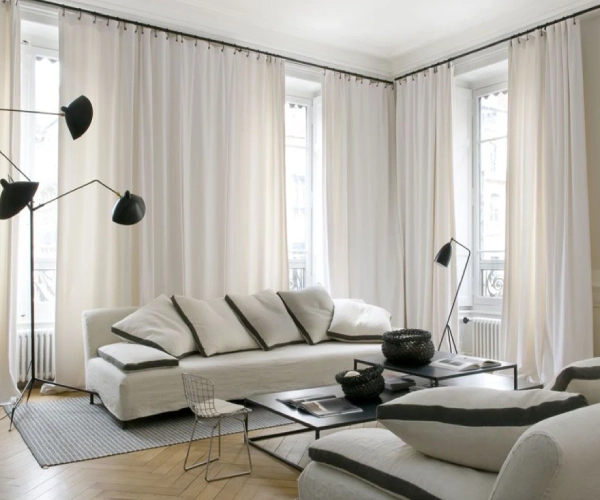 Sheer livingroom curtains flowing in sunlight, lightweight white drapes, modern airy window treatment decor.
